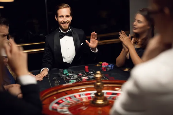 Casino fişleriyle çevrili kendinden emin bir krupiye, oyuncuları PARA BET hesaplarına giriş yapmaya davet eder.